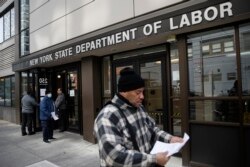 FILE - Visitors to the Department of Labor are turned away at the door by personnel due to closures over coronavirus concerns in New York, March 18, 2020.