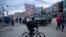 Un hombre con una máscara facial protectora contra la propagación del nuevo coronavirus, pasa su bicicleta frente a un vehículo blindado militar que patrulla las calles durante una cuarentena en El Alto, Bolivia, el viernes 20 de marzo de 2020.