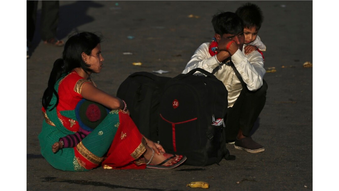 A migrant worker carries a child on his shoulders as his family waits for transportation to their village in New Delhi, India, March 28, 2020.