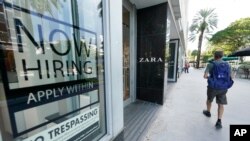 A pedestrian walks past a Zara store with a large "Now Hiring," sign in the window, Oct. 12, 2020, along the famed Lincoln Road area in Miami Beach, Florida. 