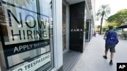 A pedestrian walks past a Zara store with a large "Now Hiring," sign in the window, Oct. 12, 2020, along the famed Lincoln Road area in Miami Beach, Florida. 