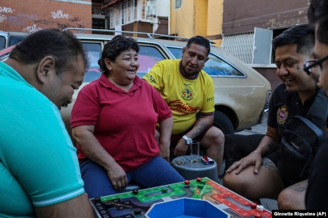 From left, Salvador Espinosa, Rosa Espinosa, Diego Castillo, Erik Cisneros and Ulises Tiscareño share a joke while playing poleana, a board game invented in prison in Mexico City, Sunday, Dec. 8, 2024. (AP Photo/Ginnette Riquelme)