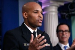 U.S. Surgeon General Jerome Adams speaks during a briefing on coronavirus at the White House, March 14, 2020, in Washington, as Treasury Secretary Steven Mnuchin listens.