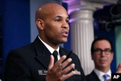 U.S. Surgeon General Jerome Adams speaks during a briefing on coronavirus at the White House, March 14, 2020, in Washington, as Treasury Secretary Steven Mnuchin listens.