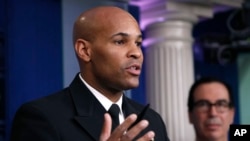 U.S. Surgeon General Jerome Adams speaks during a briefing on coronavirus in the Brady press briefing room at the White House, March 14, 2020, in Washington, as Treasury Secretary Steven Mnuchin listens. 