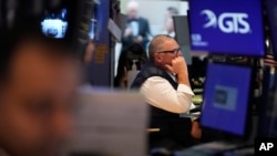 FILE - People work on the floor at the New York Stock Exchange in New York, March 4, 2025. 