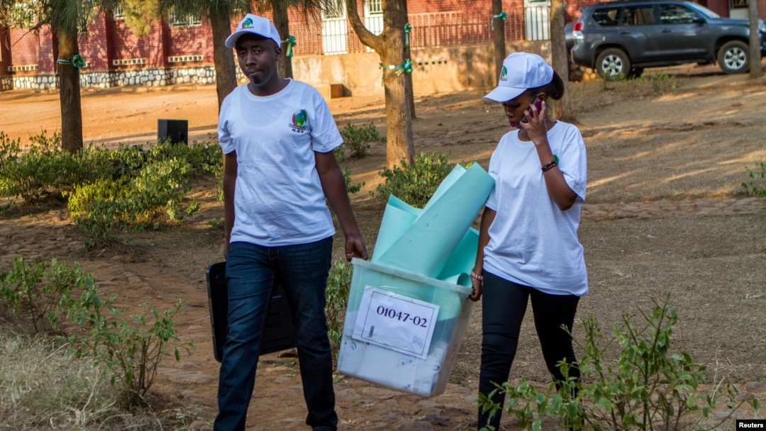 Polling staff carry a ballot box before counting at a polling center in Kigali, Rwanda, Aug. 4, 2017.