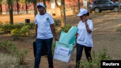 Polling staff carry a ballot box before counting at a polling center in Kigali, Rwanda, Aug. 4, 2017.