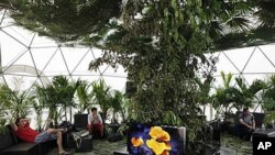 People sit in an exhibit on climate change during the United Nations Climate Change Conference in Cancun, Mexico, Dec. 1, 2010