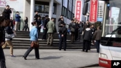 FILE - Plainclothes security personnel film as they prepare to load detained worshipers onto a waiting bus near an unregistered house church in Beijing, China, April 10, 2011.