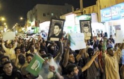 FILE - Saudi Shi'ite protesters hold Saudi flags and portraits of unidentified prisoners during a demonstration in Qatif, Saudi Arabia, March 9, 2011.