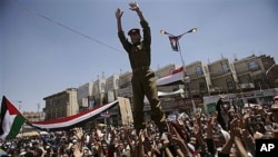 A Yemeni army officer is lifted by anti-government protesters gestures as he joins them in a demonstration demanding the resignation of President Ali Abdullah Saleh, in Sana'a, March 24, 2011