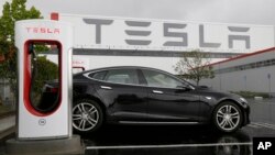 FILE - A Tesla car is parked at a charging station outside the Tesla factory in Fremont, California, May 14, 2015.