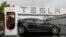FILE - A Tesla car is parked at a charging station outside the Tesla factory in Fremont, California, May 14, 2015.