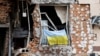 (FILE) A Ukrainian national flag hangs from a balcony of a destroyed civilian building in Irpin, Ukraine June 16, 2022.