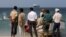 FILE - People stand on the beach as the Galaxy Leader commercial ship, seized by Yemen's Houthis, is anchored off the coast of al-Salif, Yemen, on Dec. 5, 2023.