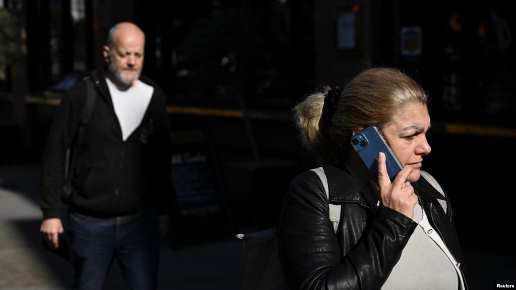 FILE - A woman holds a phone to her ear as she walks along the high street of Richmond, in London, Britain, October 11, 2024. (REUTERS/Jaimi Joy)