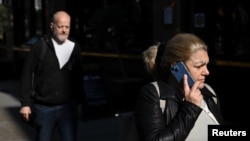 FILE - A woman holds a phone to her ear as she walks along the high street of Richmond, in London, Britain, October 11, 2024. (REUTERS/Jaimi Joy)