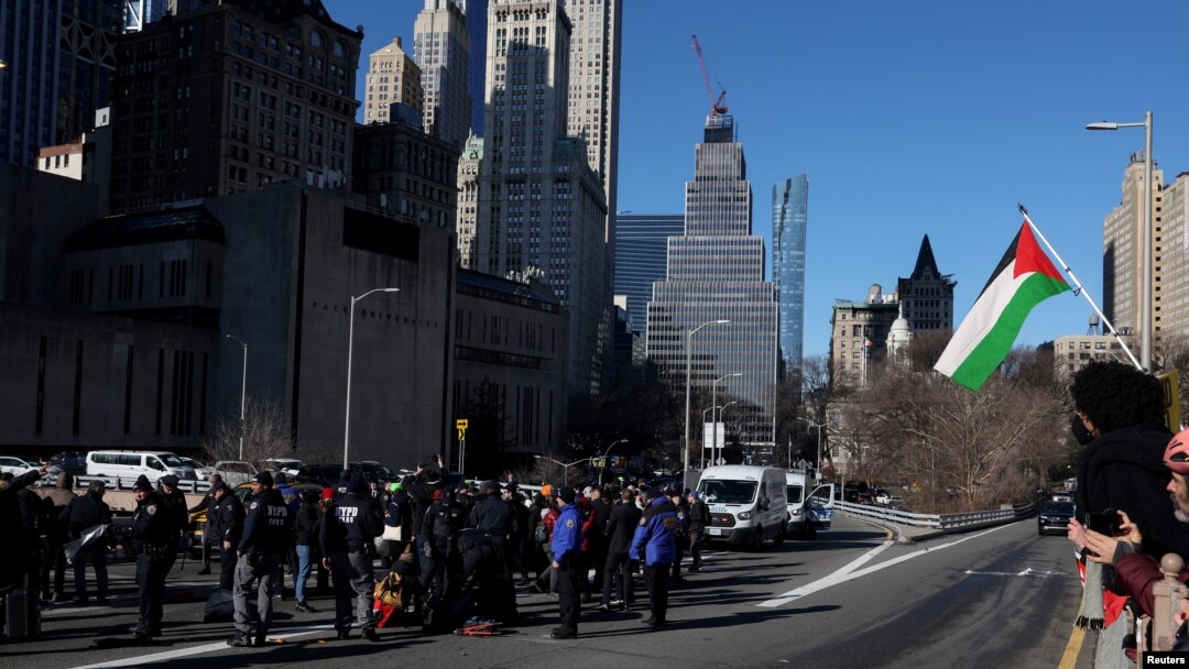 Pro-Palestinian demonstrators are taken into custody by the NYPD after blocking a Brooklyn Bridge roadway during a 'Shut it Down for Palestine' protest in New York City
