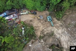 Tim penyelamat menggunakan alat berat untuk membersihkan lumpur dari jalan akibat tanah longsor yang menimpa beberapa kendaraan dan menewaskan banyak orang di Deli Serdang, Sumatera Utara, Kamis, 28 November 2024. (Binsar Bakkara/AP)