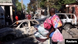 Un hombre que lleva sus pertenencias observa los restos de vehículos quemados durante el fin de semana por bandas armadas, mientras huye del suburbio de Poste Marchand, en Puerto Príncipe, Haití, el 9 de diciembre de 2024.