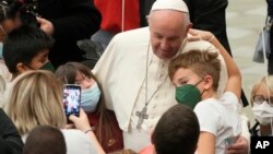 FILE - Pope Francis meets with children assisted by Santa Marta dispensary in the Paul VI Hall, at the Vatican, Dec. 19, 2021. 