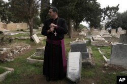 FILE - Hosam Naoum, a Palestinian Anglican bishop, pauses next to a damaged grave where vandals desecrated more than 30 graves at a historic Protestant Cemetery on Jerusalem's Mount Zion in Jerusalem, Wednesday, Jan. 4, 2023.