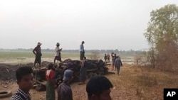 FILE - Men stand over a funeral pyre in Tar Taing village, as they prepare to cremate bodies of those found dead in the nearby village of Nyaung Yin, Myinmu township and in Tar Taing village, Sagaing township, central Myanmar on March 2, 2023. 