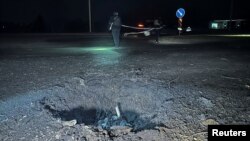 Police officers work next to a crater that appeared after a Russian drone strike, amid Russia's attack on Ukraine, in Kharkiv, Ukraine, March 26, 2024.