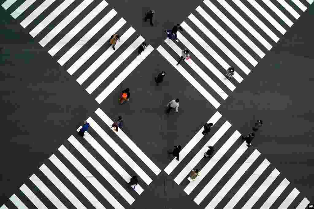 People wearing protective masks to help curb the spread of the coronavirus walk along pedestrian crossings in the Ginza shipping area of Tokyo.