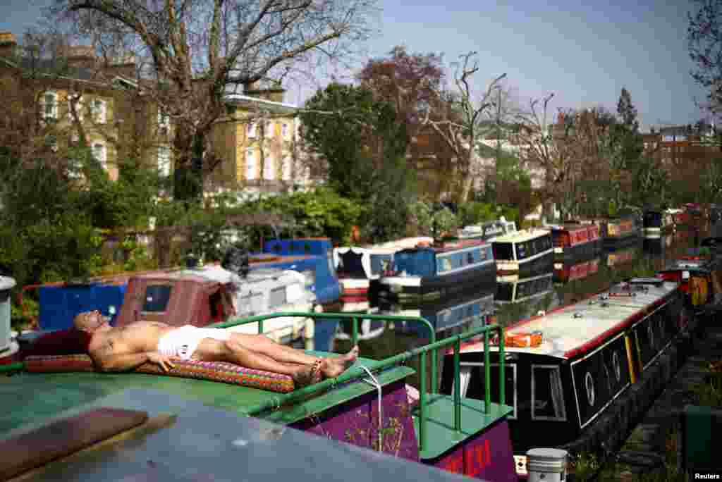 A man sunbathes on the roof of a canal boat in Little Venice as the spread of the coronavirus disease (COVID-19) continues, in London, Britain.