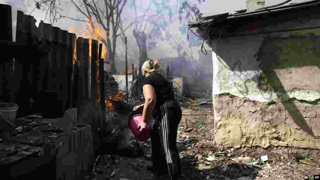 A local woman puts out the fire at her burning house after shelling in Donetsk, eastern Ukraine, Sept. 7, 2014. 