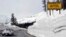 FILE - A car travels the newly plowed east entrance road over Sylvan Pass in Yellowstone National Park shortly after the park opened in this photo taken in May 2011.