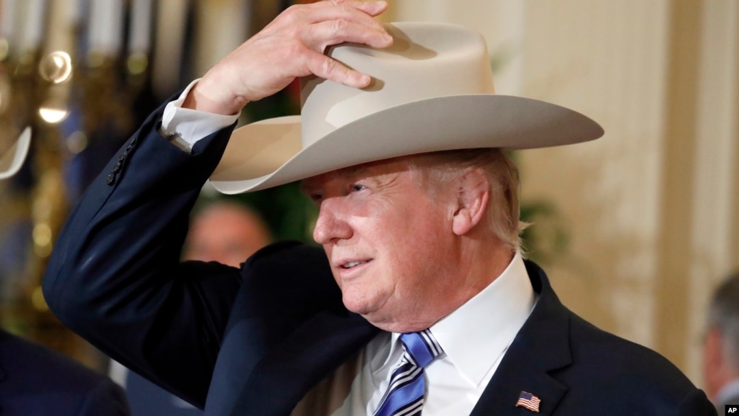 Presiden Donald Trump mencoba topi Stetson dalam pameran produksi dalam negeri “Made in Amerika” di di Gedung Putih, Washington, 17 Juli 2017. Pameran tersebut menampilkan produk-produk khas yang dibuat di setiap 50 negara bagian AS.
