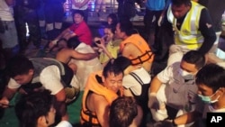 Rescued tourists from a boat that sank gather on a pier, July 5, 2018, on the island of Phuket, southern Thailand.