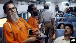 Indian 'Baul' singers perform the traditional Bengali songs of Rabindranath Tagore as they entertain passengers on board a train at Bolpur some 200 kms north of Calcutta, 11 June, 2004.