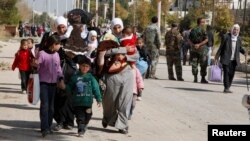 FILE - Syrian families leave the besieged town of al-Mouadamiya in Damascus countryside, Oct. 29, 2013.