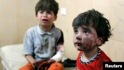 FILE - Injured children cry after, according to activists, two barrel bombs were thrown by forces loyal to Syria's president Bashar Al-Assad in Hullok neighbourhood of Aleppo.