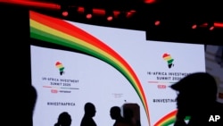 FILE - Delegates are silhouetted against the stage background before British Prime Minister Boris Johnson delivers a speech during the Opening Plenary session of the UK Africa Investment Summit in London, Jan. 20, 2020. 