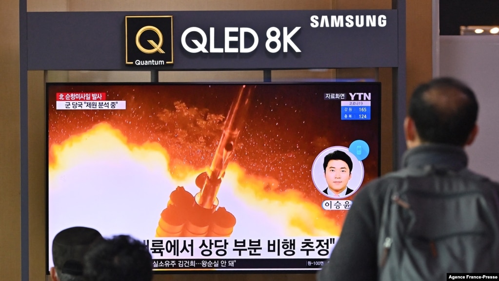 People watch a television screen showing a news broadcast with file footage of a North Korean missile test, at a railway station in Seoul on Jan. 25, 2022.