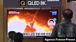 People watch a television screen showing a news broadcast with file footage of a North Korean missile test, at a railway station in Seoul on Jan. 25, 2022.