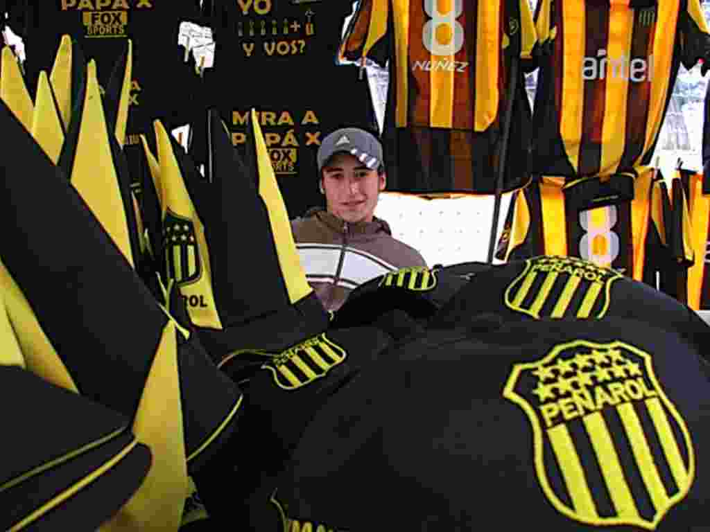Luis Merlo, de 20 años, es vendedor de banderas y camisetas. Y es hincha de Peñarol. Dijo que debido al clima lluvioso no pudo vender tanto, pero trabaja hasta las 2 de la mañana en su puesto frente al Estadio Centenario.