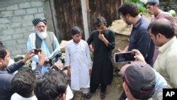 Gul Faraz, center right, and Rizwan Ullah, center left, survivors of cable car incident, talk to members of media, at near the incident site, in Pashto village, a mountainous area of Battagram district in Pakistan's Khyber Pakhtunkhwa province, Wednesday, Aug. 23, 2023. 