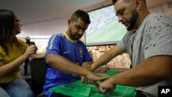 Brazil soccer fan Carlos Junior, who is both deaf and blind, experiences the World Cup match between Brazil and Mexico with the help of an interpreter who uses tactile signing and a model soccer field in Sao Paulo, Brazil, July 2, 2018. Brazil won the match 2-0.
