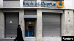 A Greek Orthodox priest walks a branch of Bank of Cyprus in Athens, March 19, 2013.