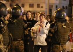A woman holding a dog talks to Belarusian law enforcement officers during an opposition protest against the inauguration of President Alexander Lukashenko in Minsk, Belarus, Sept. 23, 2020.