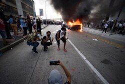 An Atlanta Police Department vehicle burns as people pose for a photo during a demonstration against police violence, May 29, 2020, in Atlanta.