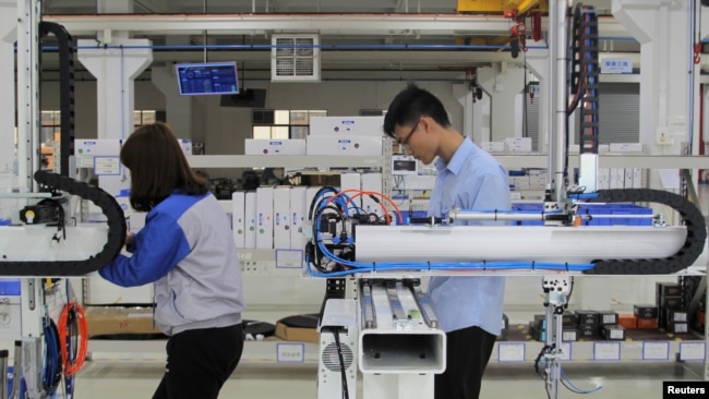 工人们在东莞一家工厂测试工业机器人。(2019年3月1日)
