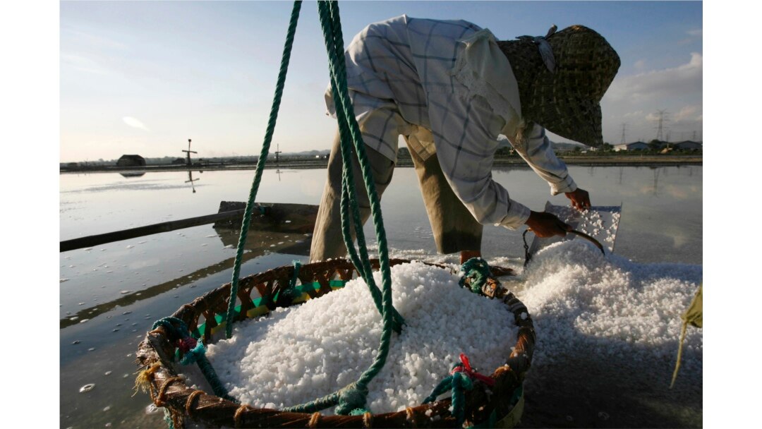 Seorang petani mengumpulkan garam saat panen di desa Benowo di provinsi Jawa Timur, Indonesia, 15 Juli 2009. Seorang petani mengaku mendapat upah sekitar $20 untuk 20 hari kerja.
