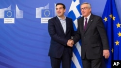FILE - European Commission President Jean-Claude Juncker, right, welcomes Greece's Prime Minister Alexis Tsipras upon his arrival at the European Commission headquarters, Brussels, Feb. 4, 2015.